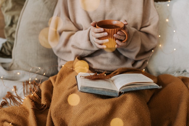 Image of person holding warm beverage and reading russian literature 
